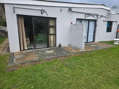 a white house with a door and a yard at Cozy Cottage in Hermanus