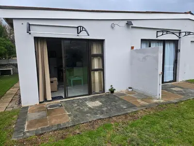 a white house with a large glass door at Cozy Cottage in Hermanus