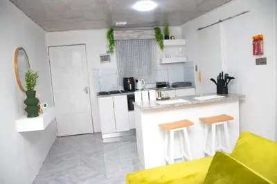 a kitchen with white cabinets and a counter with stools at Optimum Stay Self Catering Accommodation - Junior Suite in Parow