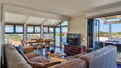 a living room with a couch and a table and a television at BluCabana 500m from Main Beach in Bettyʼs Bay