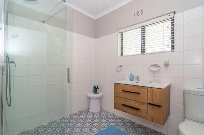 a bathroom with a shower and a toilet and a sink at Pikkewyn Paradise in Hermanus