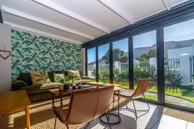 a living room with a couch and a table and chairs at Pikkewyn Paradise in Hermanus
