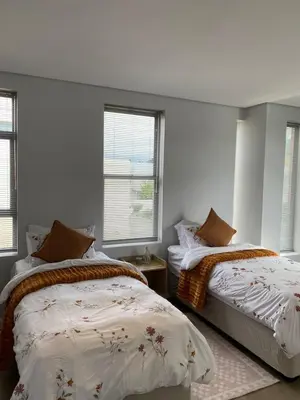a bedroom with two beds and two windows at Boerbok & Bloom in Paarl