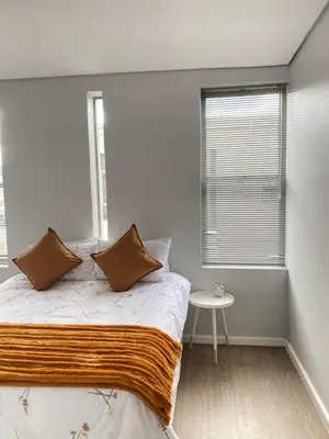 a bedroom with a bed and a window and a table at Boerbok & Bloom in Paarl