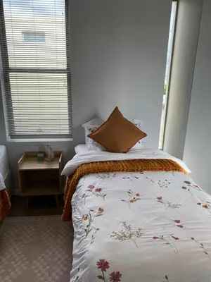 a bedroom with a bed with a floweridered comforter and a window at Boerbok & Bloom in Paarl