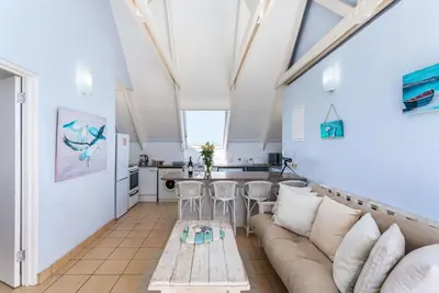 a living room with a couch and a kitchen at Dolphin Beach H305 in Cape Town