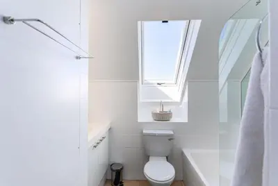 a white bathroom with a toilet and a window at Dolphin Beach H305 in Cape Town