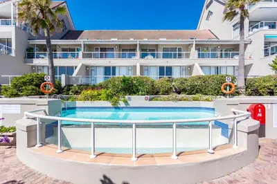 a swimming pool in front of a building at Dolphin Beach H305 in Cape Town