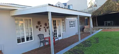a white house with awning and a chair in a yard at Firehouse guest suite no 3 in Wellington