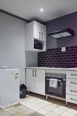 a kitchen with white cabinets and a stove and a refrigerator at Blade Flatlet in Silver Sands
