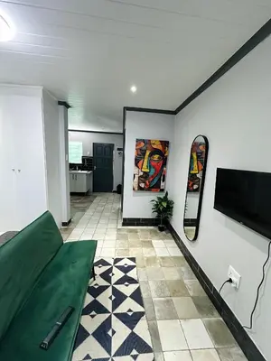 a living room with a green couch and a flat screen tv at Blade Flatlet in Silver Sands