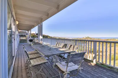 a porch with chairs and a table and a grill at Nordic Family Beach House in Bettyʼs Bay
