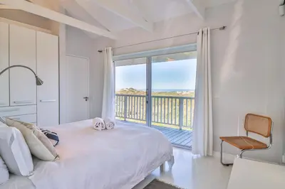 a bedroom with a bed with a view of a balcony at Nordic Family Beach House in Bettyʼs Bay