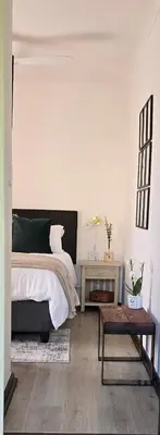 a white bedroom with a bed and a table at Petite Vine in Stellenbosch
