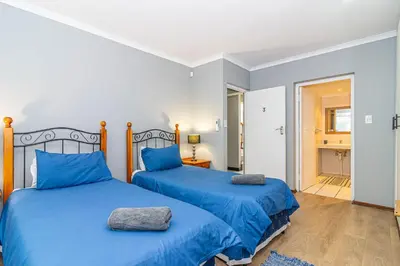 two beds in a bedroom with blue comforter at Four Pines in Hermanus