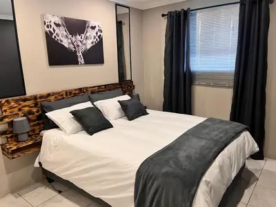 a bedroom with a large white bed with black pillows at Casa Bracken in Windsor Park