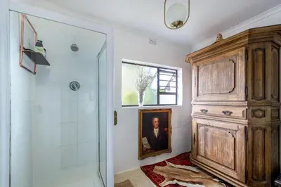 a bathroom with a shower and a painting of a man at The smallest farm in Africa ELGIN in Grabouw