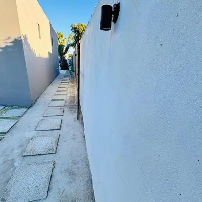 an alley with a white wall next to a building at Browns villa and construction pty ltd in Cape Town