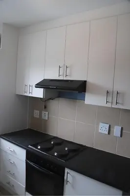 a kitchen with a stove and white cabinets at Browns villa and construction pty ltd in Cape Town