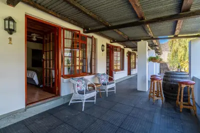 a porch of a house with chairs and a barrel at Grietjiesdrif- Mountain Retreat in Rawsonville