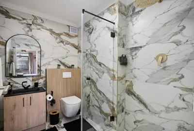 a bathroom with a shower with a marble wall at 8 Sleeper Luxury Duplex Penthouse in Cape Town