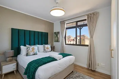a bedroom with a large bed with a green headboard at 8 Sleeper Luxury Duplex Penthouse in Cape Town
