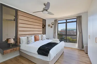a bedroom with a large bed and a large window at 8 Sleeper Luxury Duplex Penthouse in Cape Town