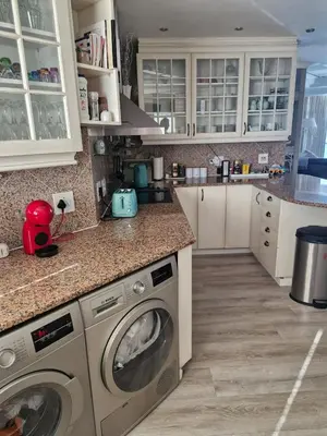 a kitchen with white cabinets and a washer and dryer at PENTHOUSE Luxury Apartment Amazing Sea Views CAPE TOWN in Strand