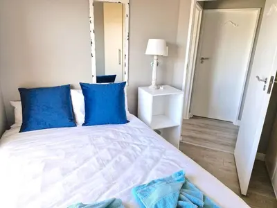 a bedroom with a large bed with blue pillows at PENTHOUSE Luxury Apartment Amazing Sea Views CAPE TOWN in Strand