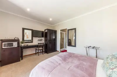 a bedroom with a bed and a desk and a tv at Tambula Guest House in Cape Town