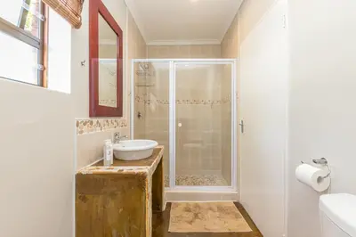 a bathroom with a shower and a sink at Tambula Guest House in Cape Town