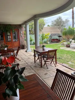 a patio with benches and a table and a swing at Tambula Guest House in Cape Town
