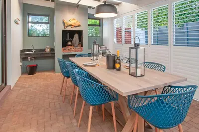 a dining room with a wooden table and blue chairs at Tree Fern Cottage in Hermanus