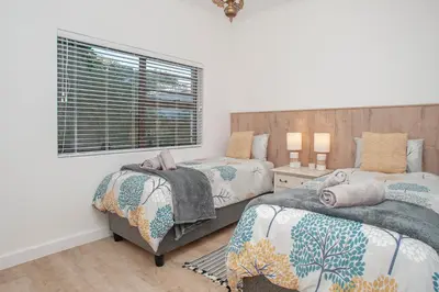 a bedroom with two beds and a window at Tree Fern Cottage in Hermanus