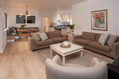 a living room with two couches and a table at Tree Fern Cottage in Hermanus