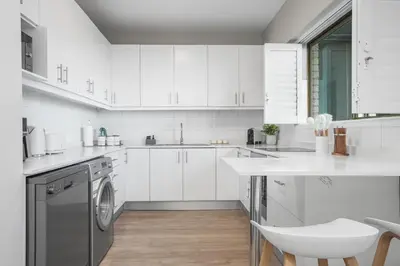 a white kitchen with white cabinets and a dishwasher at Searenity Tides in Cape Town