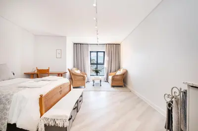 a white room with a bed and two chairs at Olyfberg Rus in Paarl