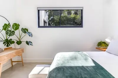 a bedroom with a bed and a window at Contemporary Apartment With Shared Swimming Pool in Stellenbosch