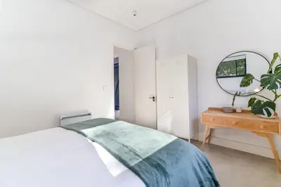 a bedroom with a bed and a mirror and a table at Contemporary Apartment With Shared Swimming Pool in Stellenbosch