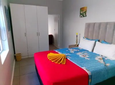 a bedroom with a bed with a red and blue blanket at Neo & Ruks Guest house parow 1 in Avondale