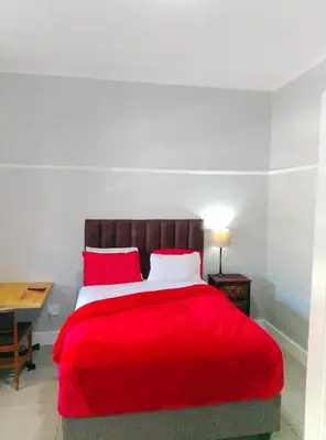a bedroom with a red bed with a desk at Neo & Ruks Goodwood 1 in Goodwood