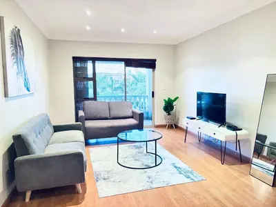 a living room with a couch and a tv at Spanish Charm in the Heart of Century City Stylish Stay Near Canal Walk! in Cape Town