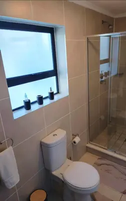 a bathroom with a toilet and a shower and a window at Blouberg Luxury Oasis With Pool & Scenic Mountain Views in Cape Town