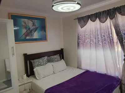 a bedroom with a bed with a purple blanket and a window at Neats Accommodations in Cape Town