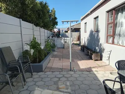 a patio with chairs and tables and a wall at Neats Accommodations in Cape Town