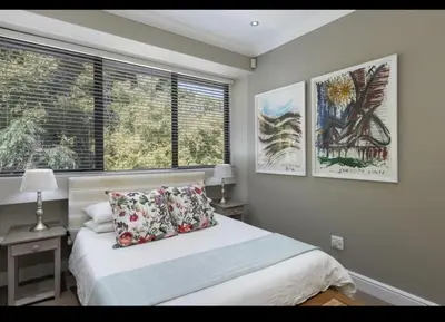 a bedroom with a bed with two lamps and two windows at Merweda Wag-n-Bietjie on Dorp Street in Stellenbosch