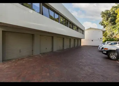 a large building with four garage doors and a parking lot at Merweda Wag-n-Bietjie on Dorp Street in Stellenbosch