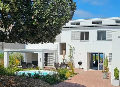 a white house with a patio and a courtyard at Tamatiebank in Hermanus