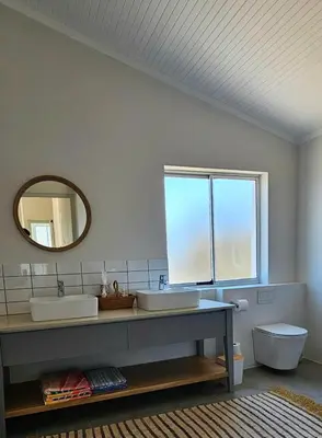 a bathroom with two sinks and a mirror at Tamatiebank in Hermanus
