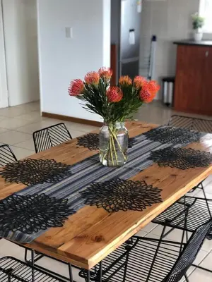a wooden table with a vase of flowers on it at Brackenfell self catering accommodation in Brackenfell